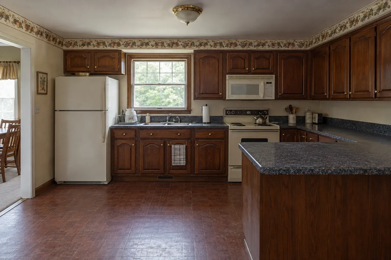 Dark cherry U-shaped kitchen with a dark tile floor before remodeling
