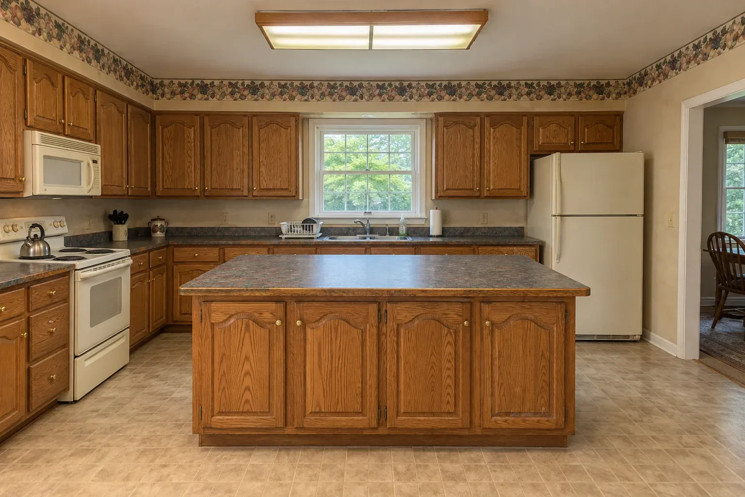 Honey oak kitchen with a wallpaper border and laminate counters before remodeling